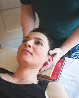 Image shows practitioner's hands on the student's head.